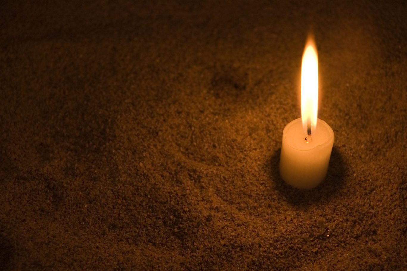 candle burning low in the sand