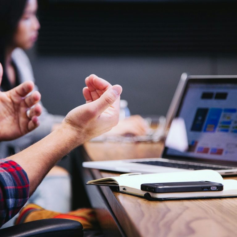 a tight photo angle of someone's hands in-front of a Mac during a meeting.